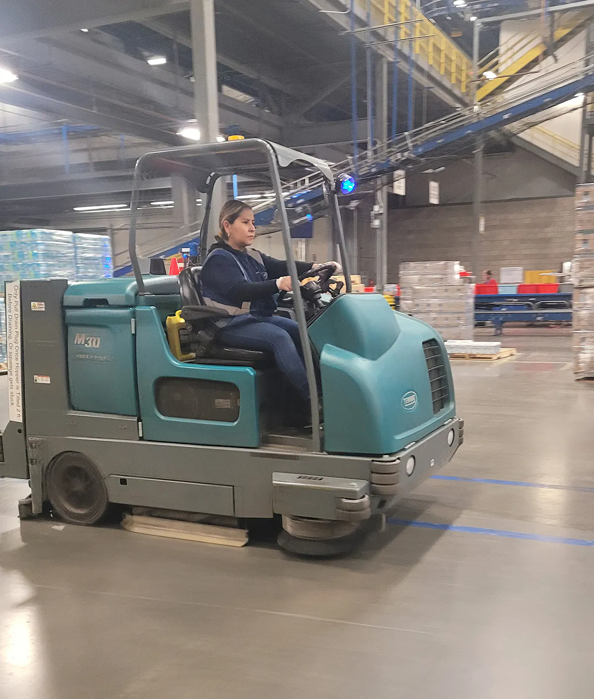 KBS crew member operates cleaning machinery in a warehouse