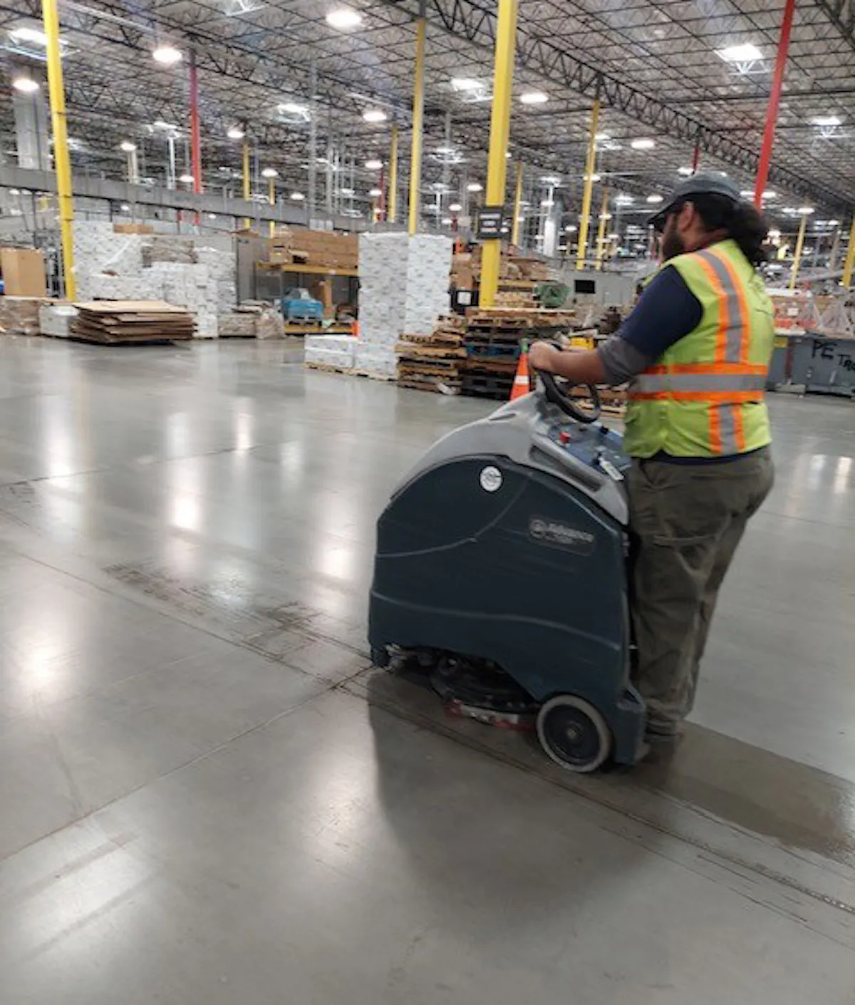 KBS crew member operates a floor cleaner in a warehouse